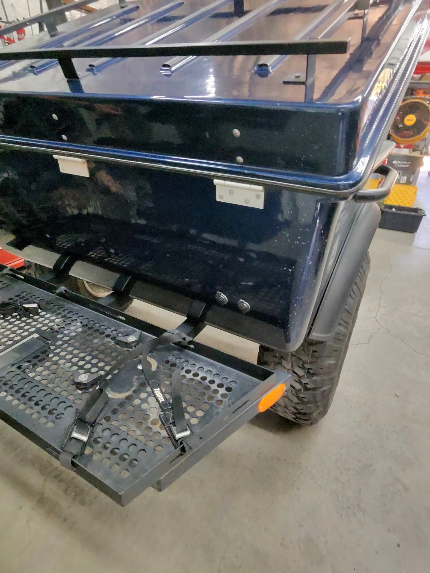 RV rental ready: Dark blue hardshell rooftop tent with a rear cargo rack and off-road tire. Adventure travel storage. — photo 7