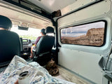 Cozy RV rental interior on a scenic road trip, with desert mesas visible through the side window.