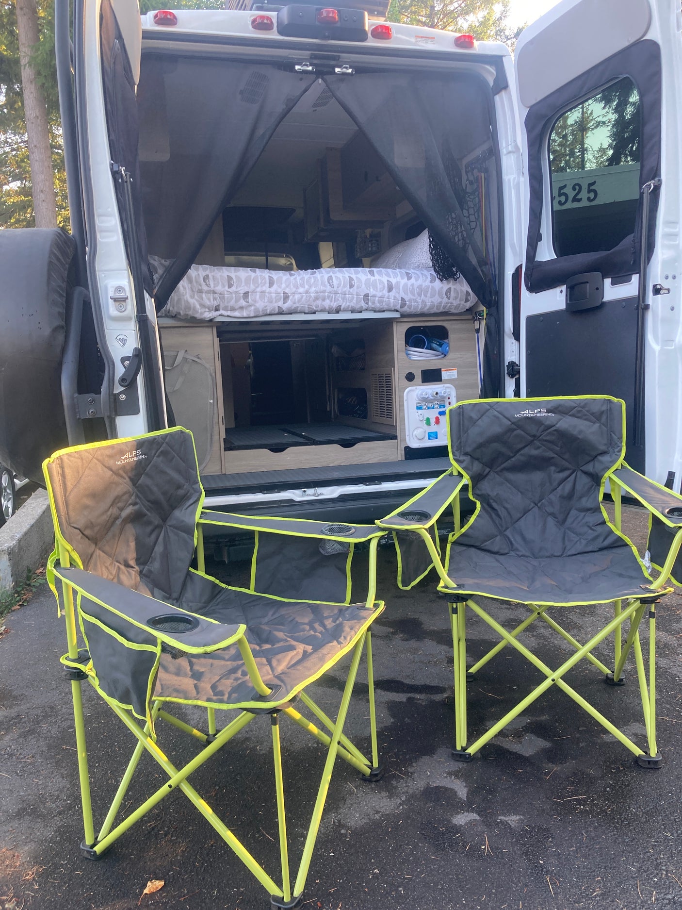 Relaxing outdoors with an RV rental! A cozy camper van with bug screen and two comfy chairs for your adventure.