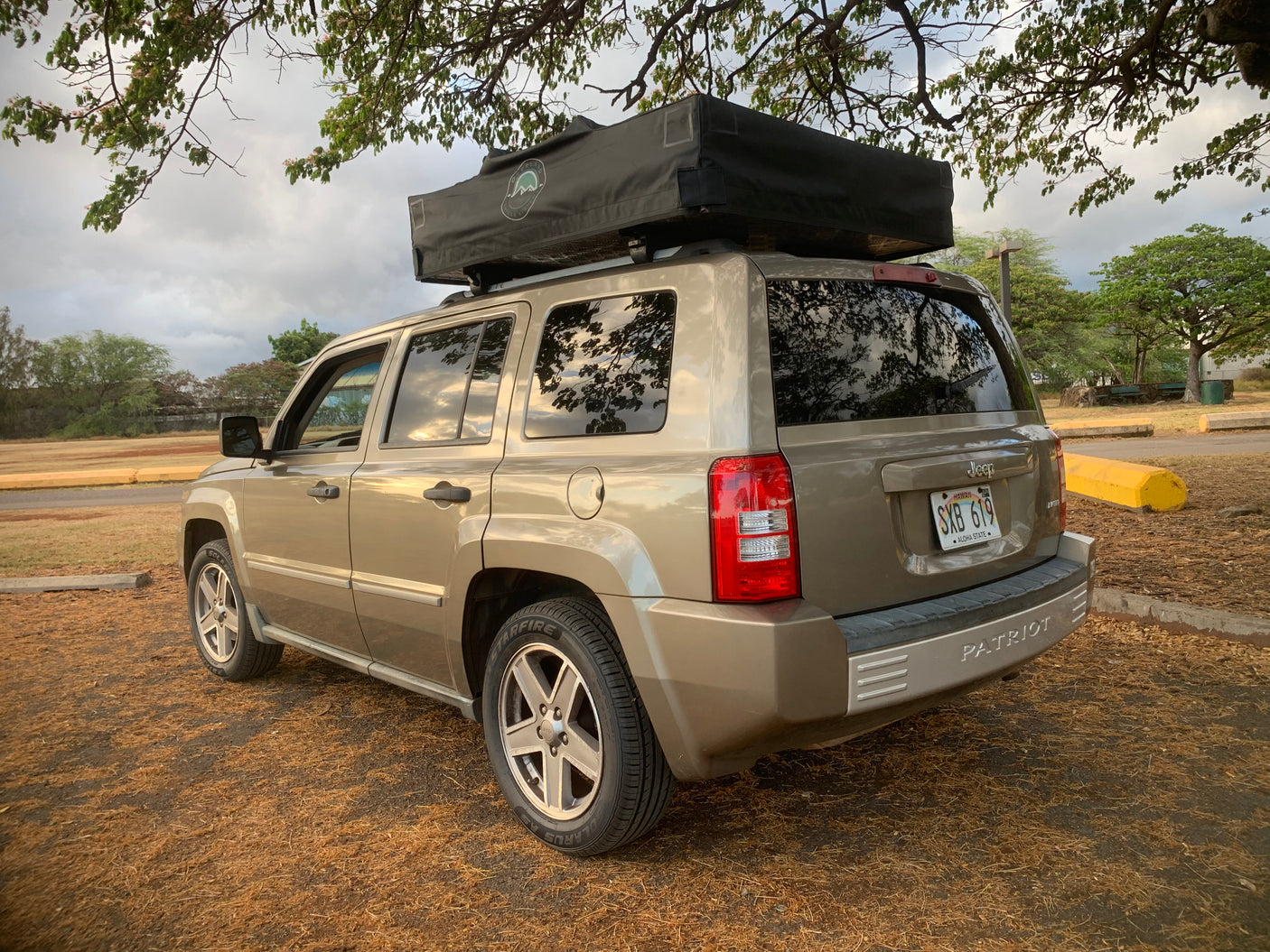 Tan Jeep Patriot SUV with black rooftop tent, ideal for your next Hawaii RV rental adventure.