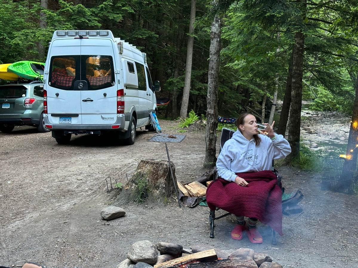 Relaxing by a campfire with an RV rental van and a car carrying kayaks in a lush forest, perfect for outdoor adventure. — photo 5