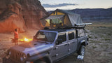 Camping in the desert: A Jeep Gladiator with rooftop tent, campfire, and child. Book your RV rental adventure!