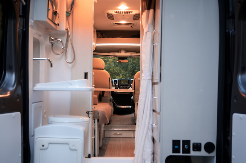 Interior of an rv rental camper van. From the rear, view of compact bath, living area, and driver's cab. Ready for travel! — photo 17