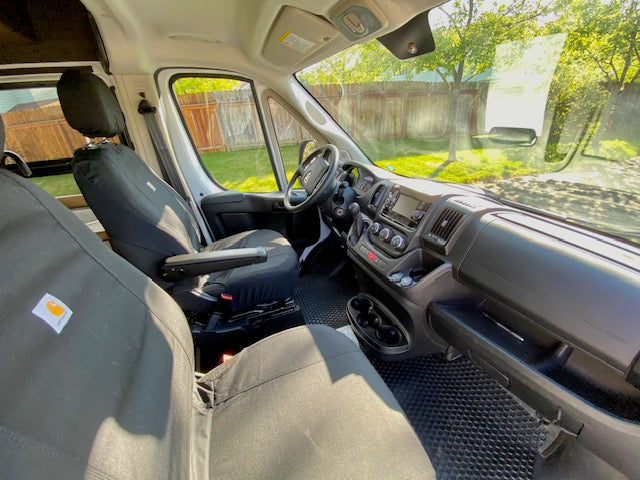 Inside an RV rental, showing the clean front cabin: black seats with armrests, a dashboard, and open storage. — photo 13