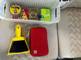 Organized RV rental: Basket of games (Spot It!, UNO, cards) for travel entertainment, with a handy dustpan and red case on the cream seats.