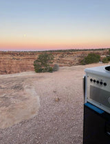 Stunning desert canyon vista at sunset with a moon, seen from an RV rental. Perfect for outdoor adventure travel.