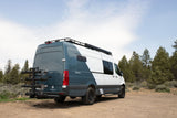 Teal and white Sprinter camper van with bike rack, ready for your RV rental outdoor adventure.