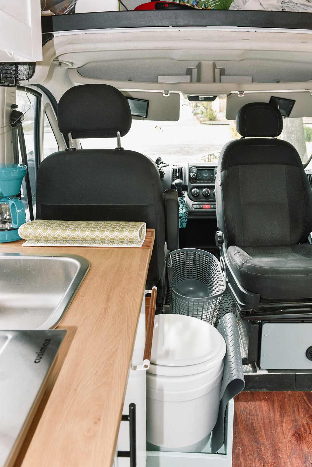 Explore this efficient rv rental van interior featuring a kitchenette, portable toilet, and front cabin view.