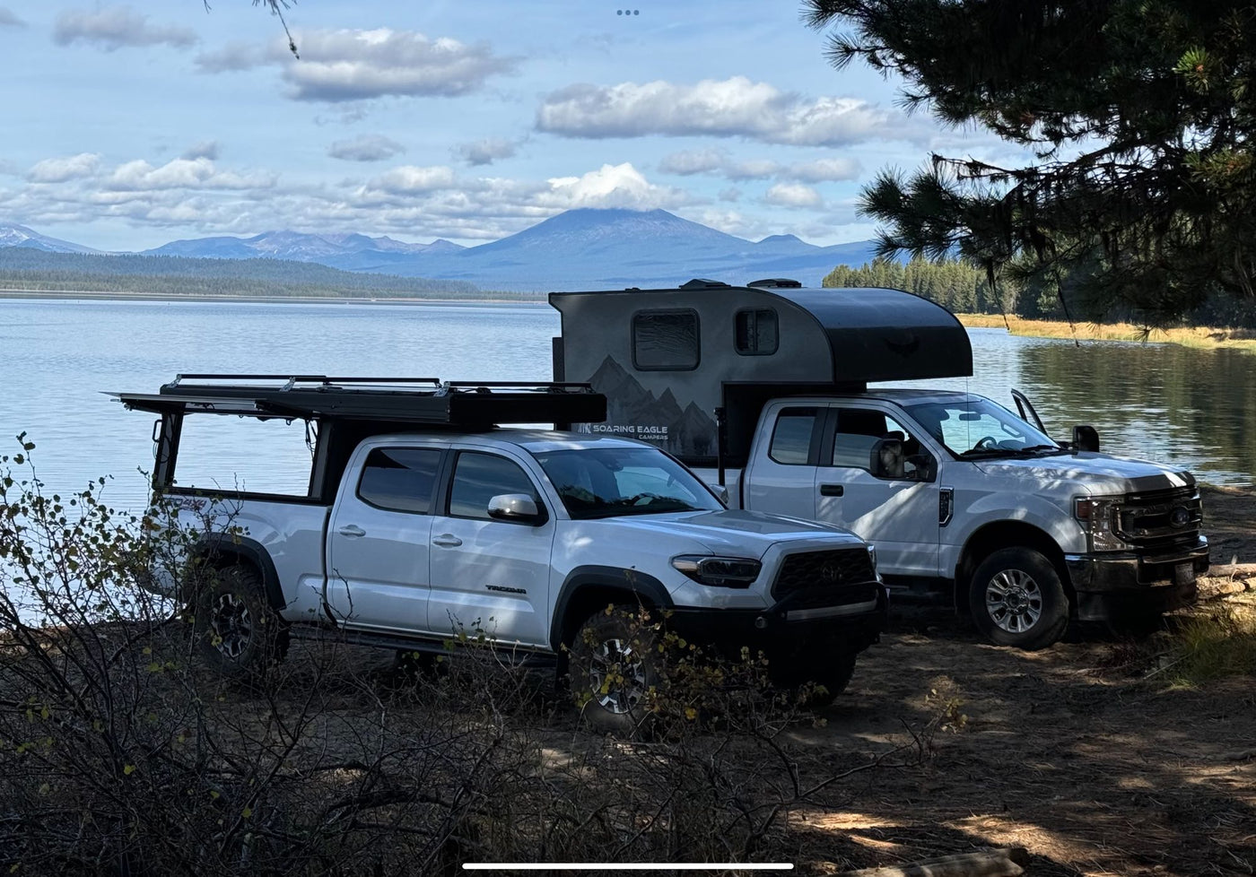  in a forest setting.|Frosted RV rental truck camper parked at a misty lakeside campsite. Ideal for outdoor adventures.|Enjoy nature with this truck camper and Tacoma with rooftop tent parked lakeside. An ideal RV rental for overlanding adventures.|White truck with Soaring Eagle truck camper (an RV rental type) — photo 7