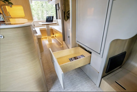 Modern RV rental interior with kitchen, dinette, and an open storage drawer. Ideal for comfortable travel.