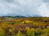 Vibrant autumn foliage (yellow, orange, red) blankets hills before snow-capped mountains. Plan your scenic RV rental trip!
