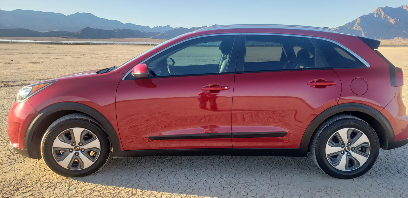 Red crossover SUV in a desert landscape with mountains. Explore with this RV rental alternative for your next adventure.