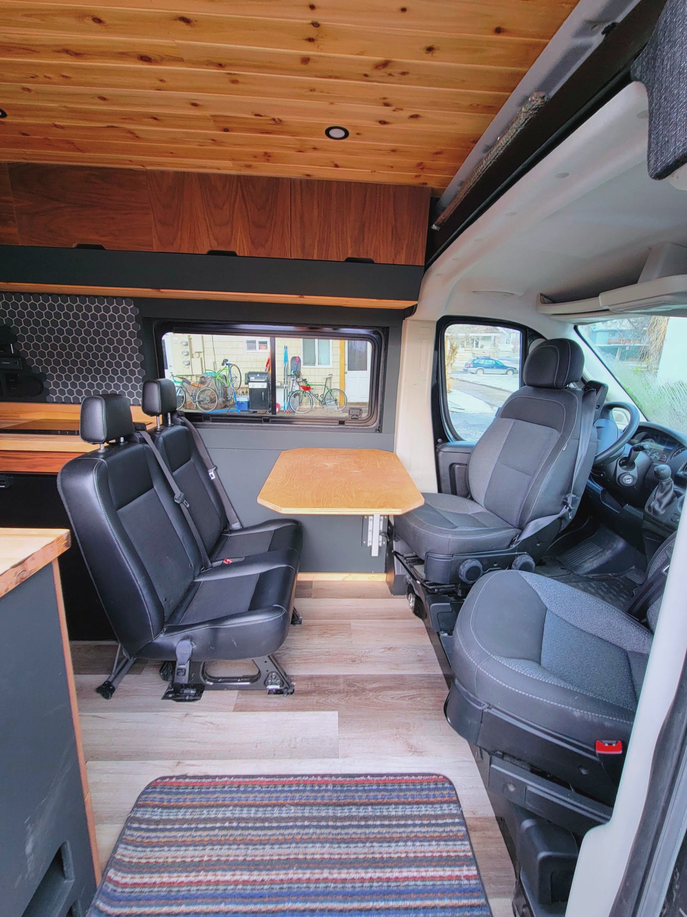 RV rental: Inside a camper van featuring a dining area with two rear-facing seats, a table, and wooden decor.