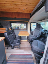RV rental: Inside a camper van featuring a dining area with two rear-facing seats, a table, and wooden decor.