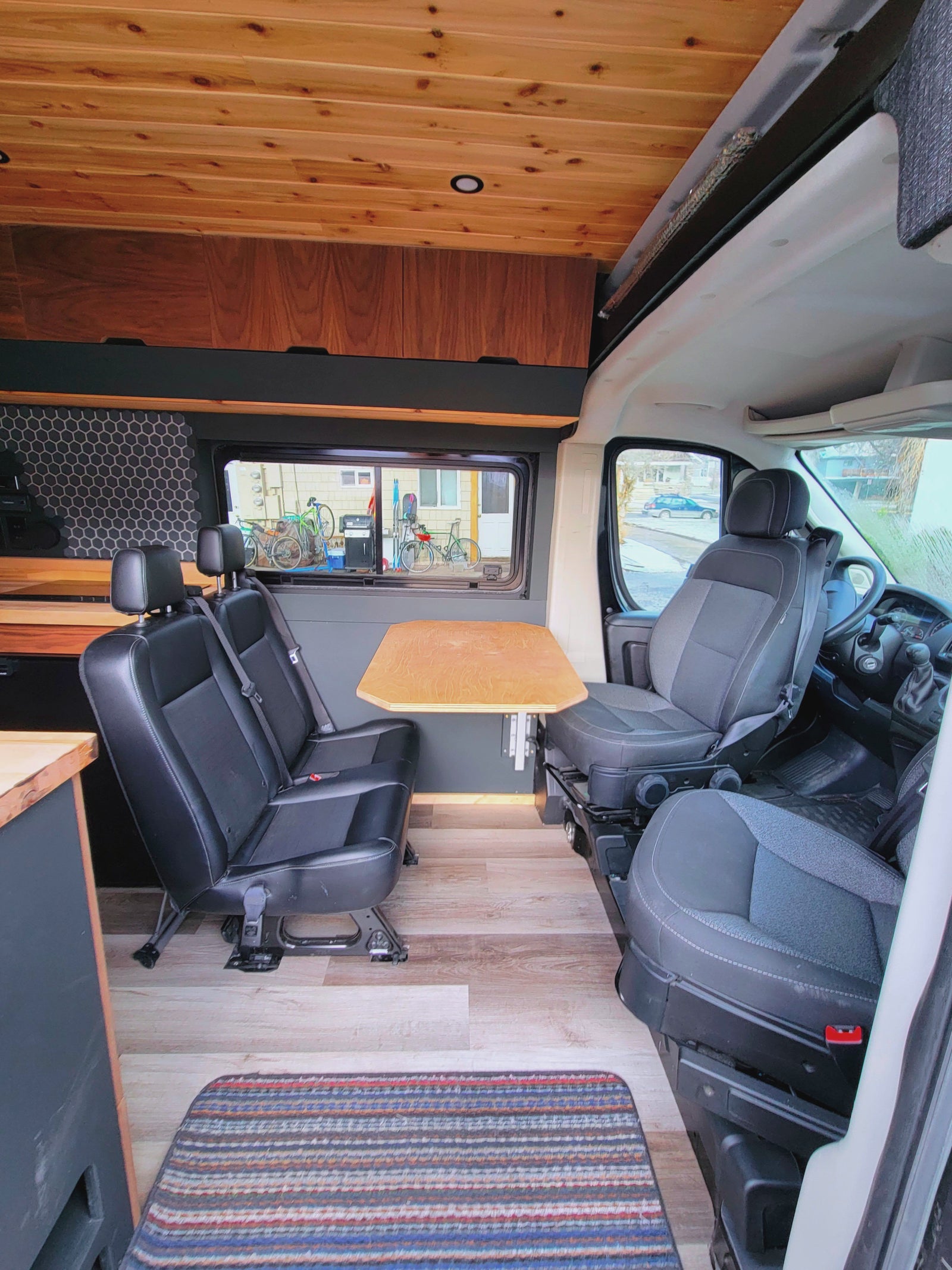 RV rental: Inside a camper van featuring a dining area with two rear-facing seats, a table, and wooden decor.