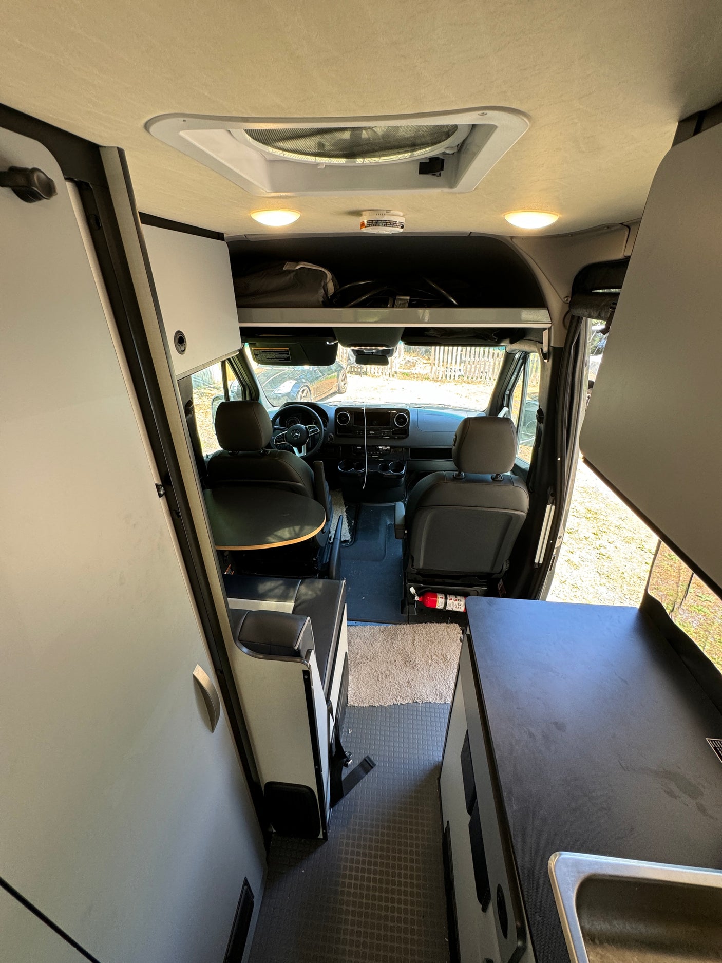Spacious camper van interior, ideal for RV rental adventures. Features kitchen, seating, and driver's cab.