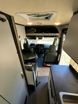 Spacious camper van interior, ideal for RV rental adventures. Features kitchen, seating, and driver's cab.