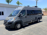 Modern gray RAM Tellaro rv rental camper van parked outside. Palm trees and a building are visible in the background.