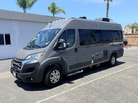 Modern gray RAM Tellaro rv rental camper van parked outside. Palm trees and a building are visible in the background.