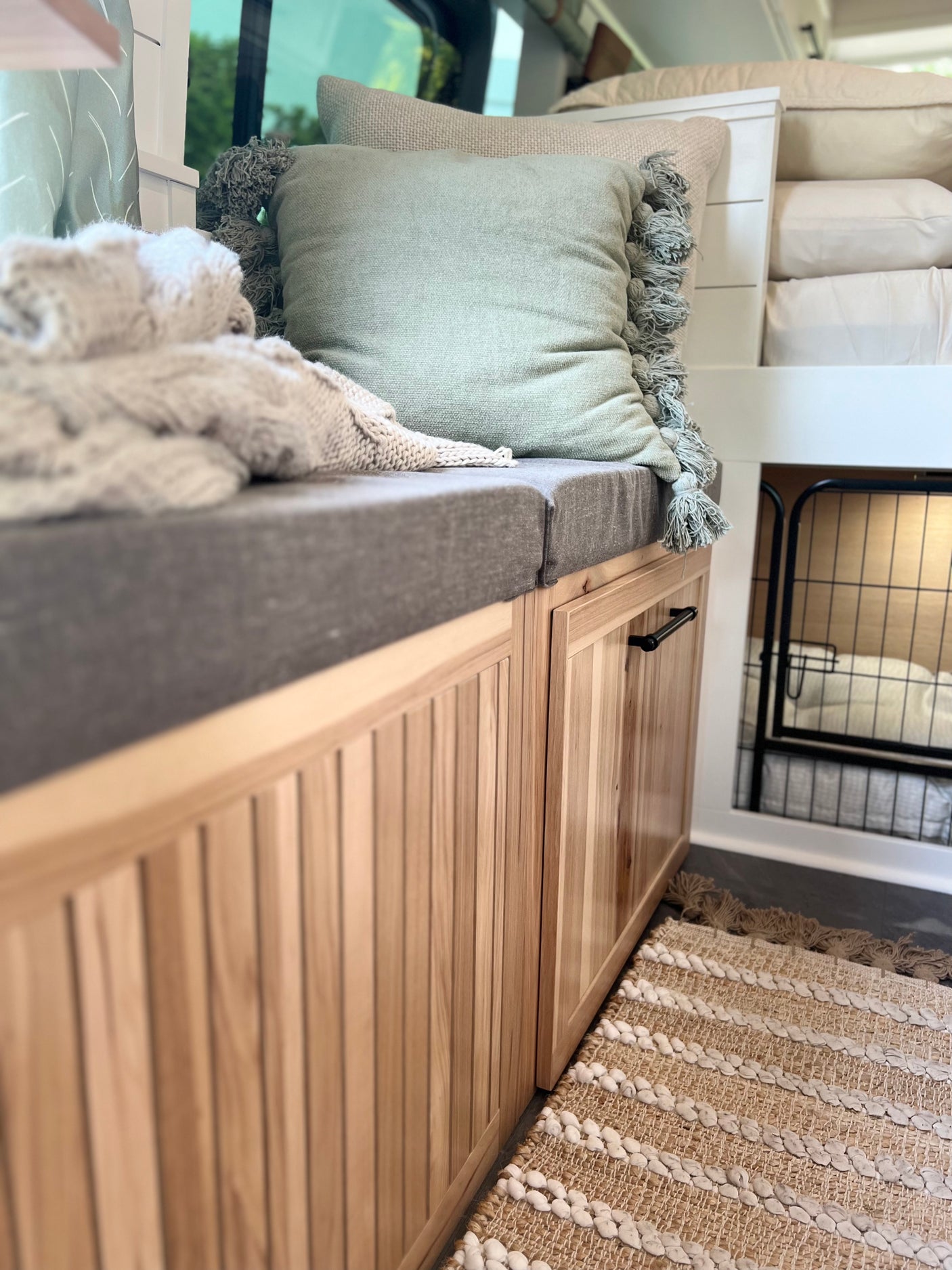 This cozy RV rental features a bench seat with plush cushions, wood cabinets, and a built-in pet kennel.