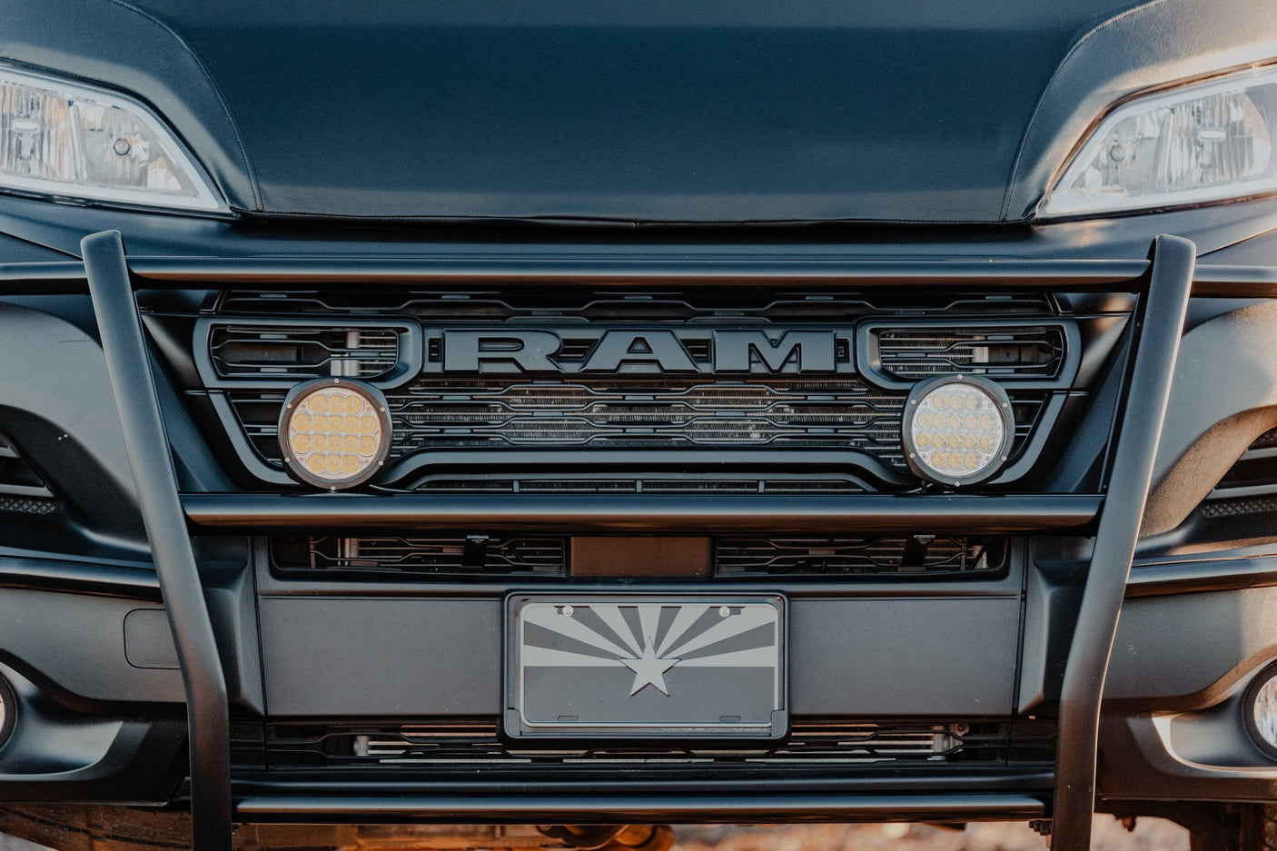 Front of a black Ram RV rental with off-road lights, bull bar, and an Arizona flag license plate.