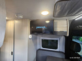 Inside an rv rental: TV with Peacock, essential smoke/CO detectors, window, and seating. Compact living at its best.