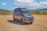 Adventure-ready Mercedes Sprinter RV rental camper van, dark gray with yellow accents, on a scenic dirt overlook.
