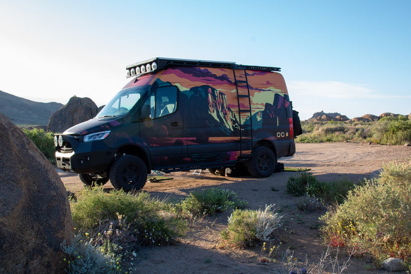  and chairs. Perfect for outdoor adventures.|Custom RV rental parked in a desert landscape. This black adventure van features a vibrant mural — photo 10