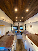 This RV rental's spacious, modern interior features a rich wooden ceiling, white cabinetry, and comfy bench seating.