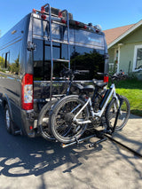 Winnebago Travato RV rental with two e-bikes on a rear rack, parked outside, ready for travel.