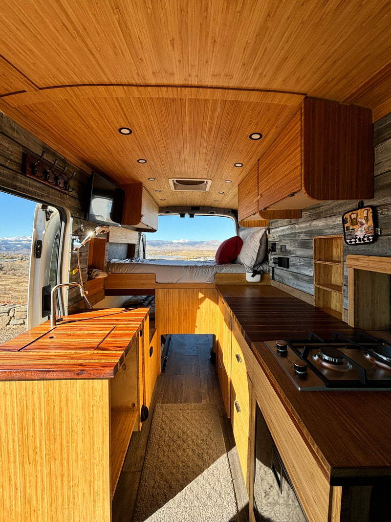 Cozy camper van interior with bamboo finishes, kitchenette, bed, and a scenic mountain view, perfect for your next rv rental adventure. — photo 1