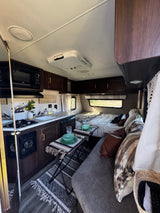 Inviting RV rental interior for glamping. Features a kitchen, dining area, bed, and cozy living space.