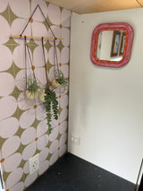 Inside an RV rental: Floral wall tiles, hanging plants, and a pink mirror create a cozy, decorated space with countertop & outlets.