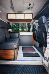 Spacious and well-designed RV rental interior featuring a bench seat, custom cabinetry, and a bright living area.