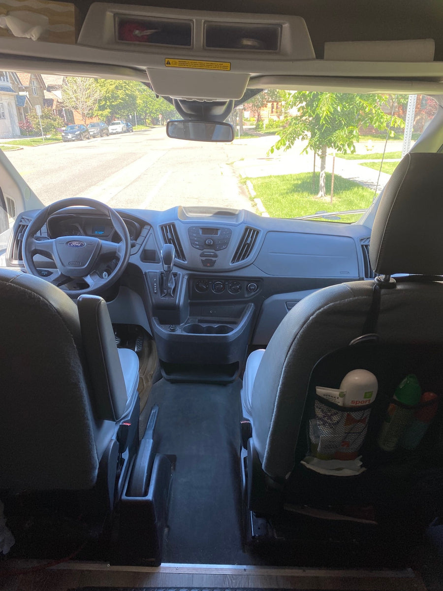 Inside an RV rental van: dashboard, steering wheel, and street view through the windshield, ready for road trips.