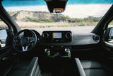 RV rental interior: Dashboard, nav screen (CA map), and green mugs. Road ahead visible for your next adventure.