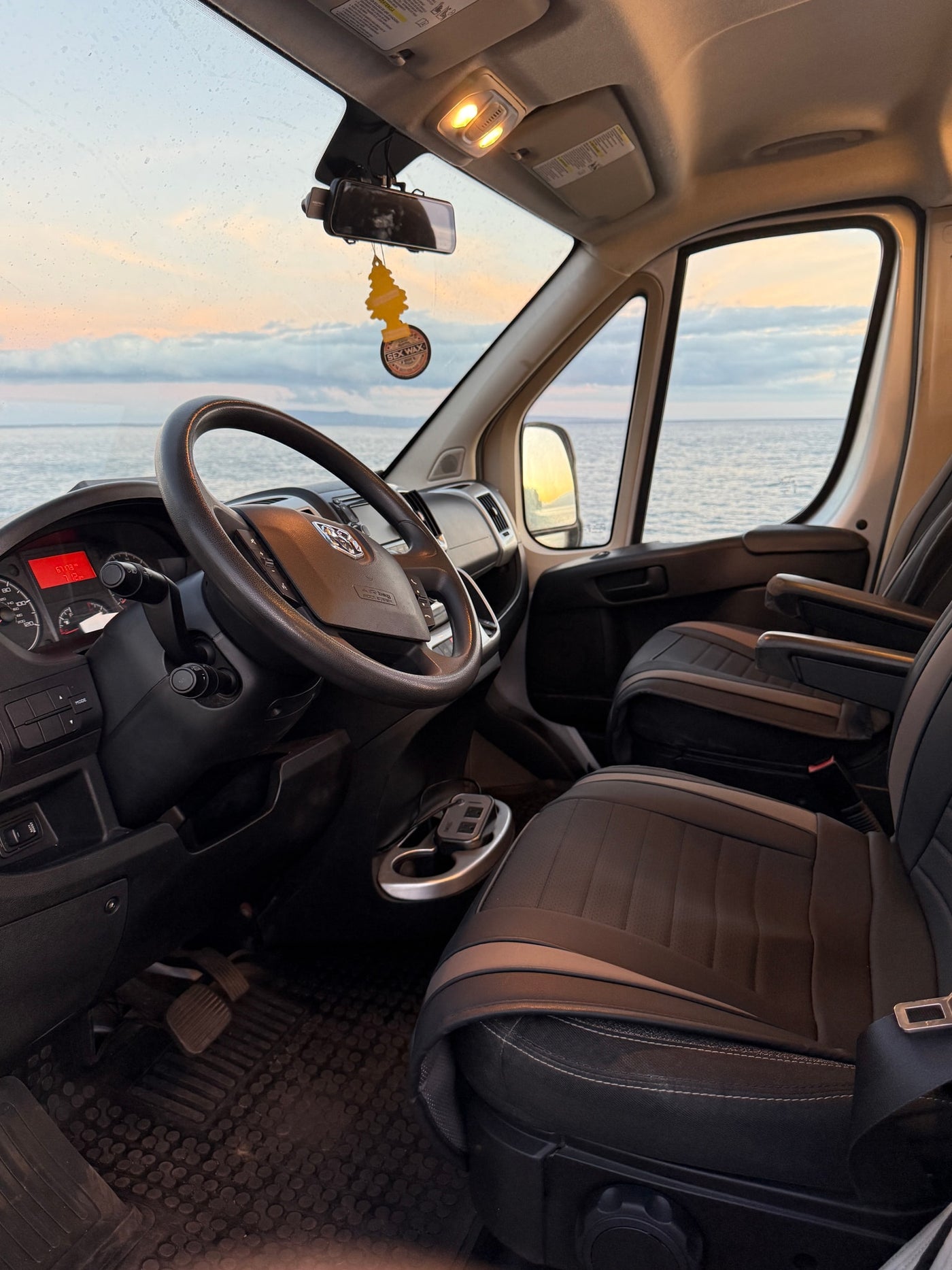 Stunning RV rental interior: driver's seat perspective overlooking a serene ocean at sunset, perfectly capturing the tranquility of travel. — photo 7