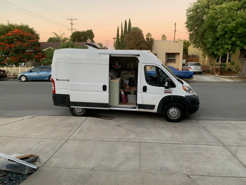 Customized Ram ProMaster campervan, potentially an rv rental, with its side door open, revealing a cozy interior parked on a residential street. — photo 6