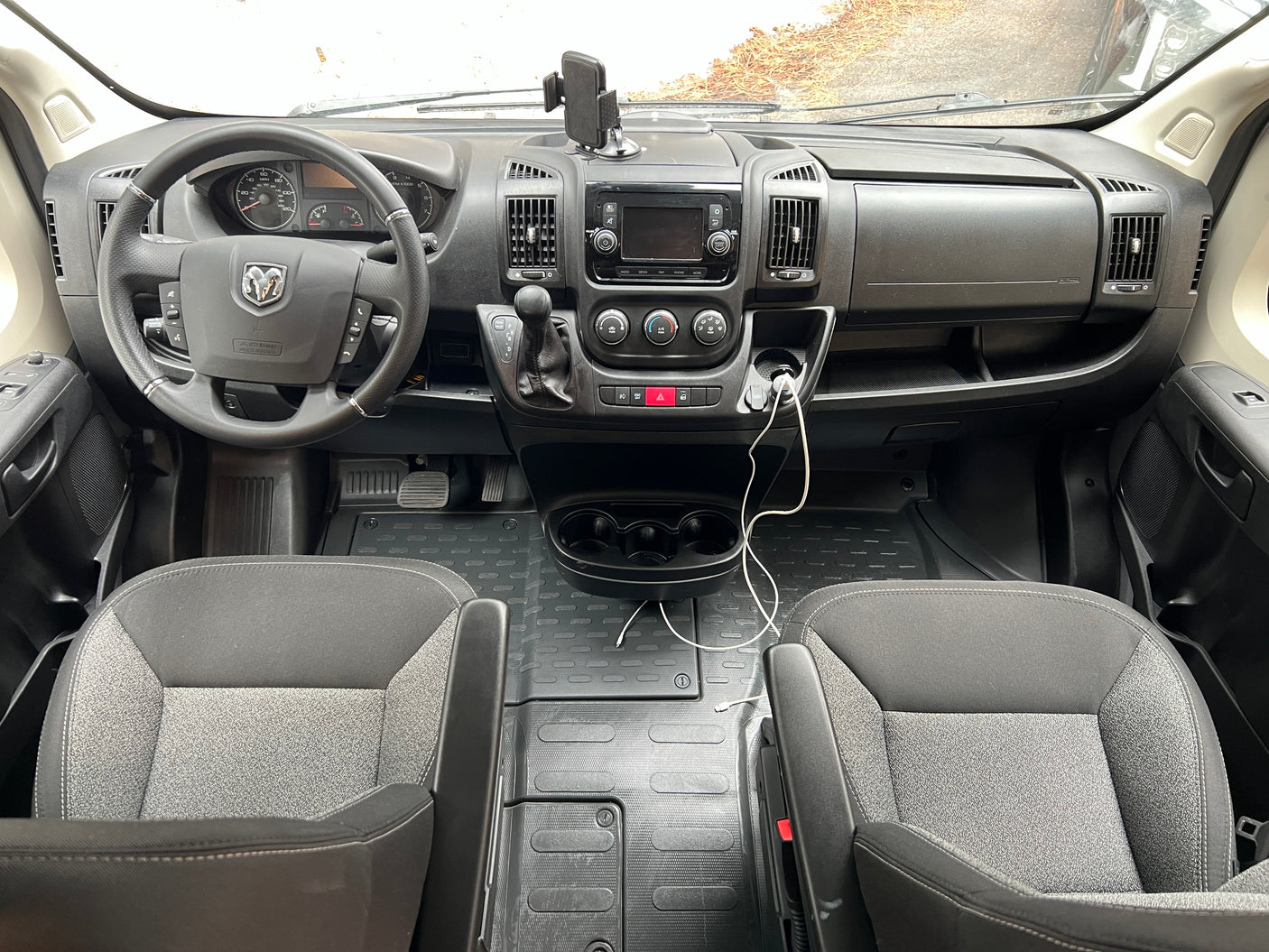 Inside an rv rental: the spacious front cabin with steering wheel, dashboard, gear shifter, and comfortable seating.