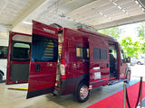 This red Winnebago Solis RV rental van is showcased on a red carpet with all doors open.
