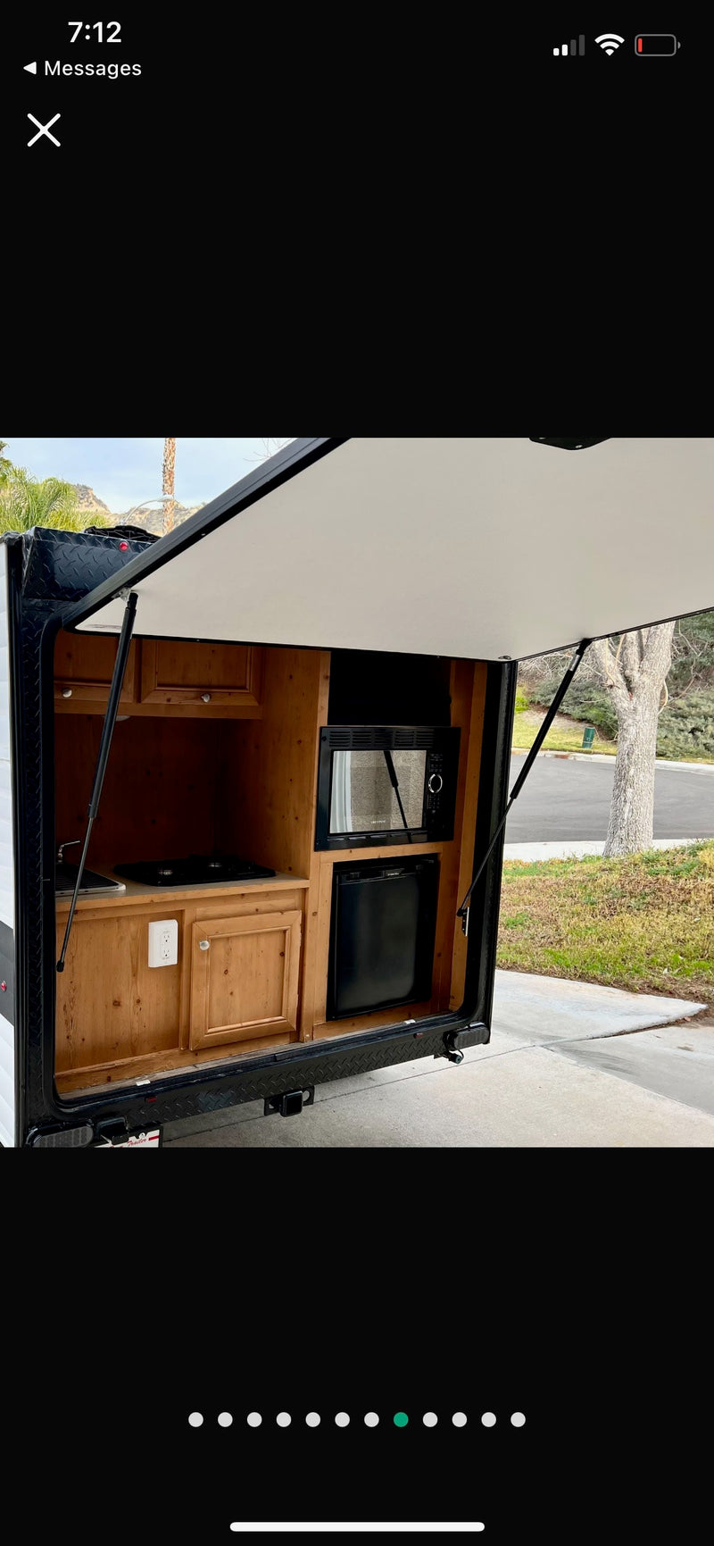 RV rental: Discover this outdoor kitchen, featuring a microwave, mini-fridge, stovetop, and wood cabinets, perfect for camping trips. — photo 5