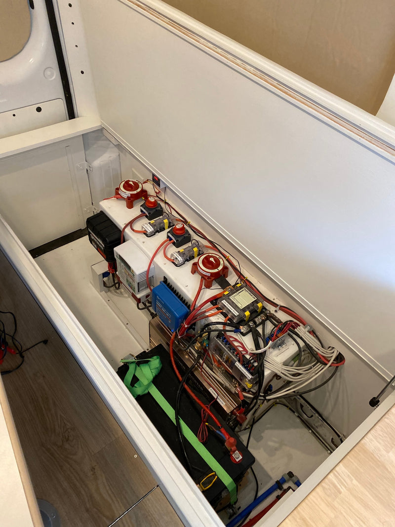 Inside an RV rental, this image displays a complex, neatly wired electrical system with batteries, inverter, and solar controller. — photo 12