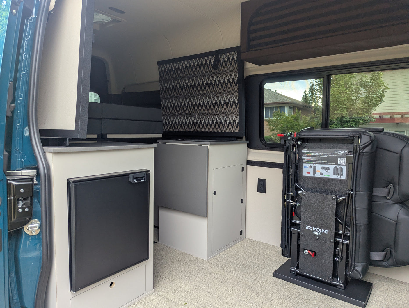 Explore this rv rental camper van interior: compact kitchenette with fridge, clever storage, and adaptable EZ Mount seating system.