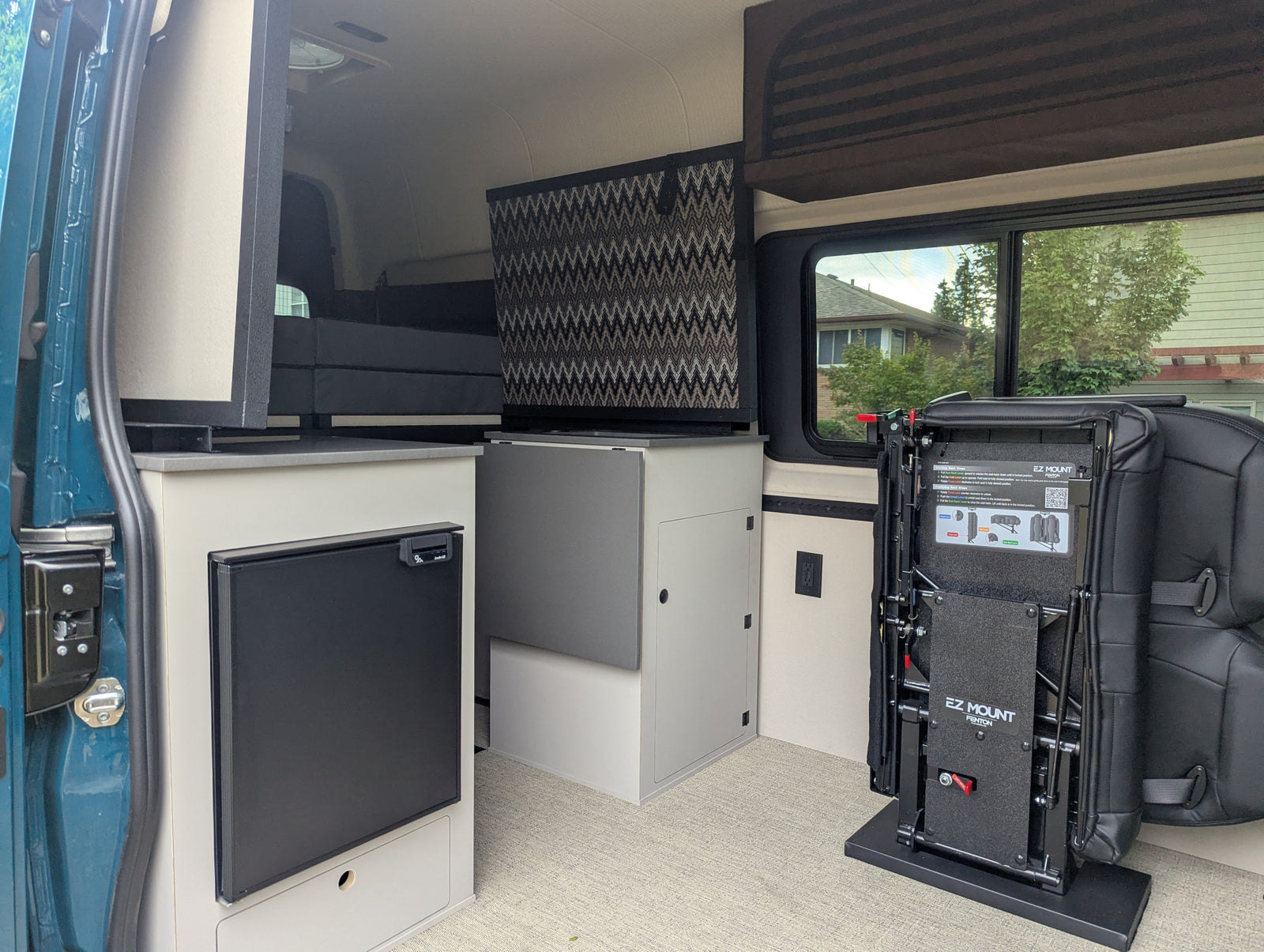 Explore this rv rental camper van interior: compact kitchenette with fridge, clever storage, and adaptable EZ Mount seating system.