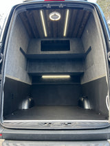 RV rental van's organized cargo space: wood ceiling, shelving, textured floor, and bright lighting.