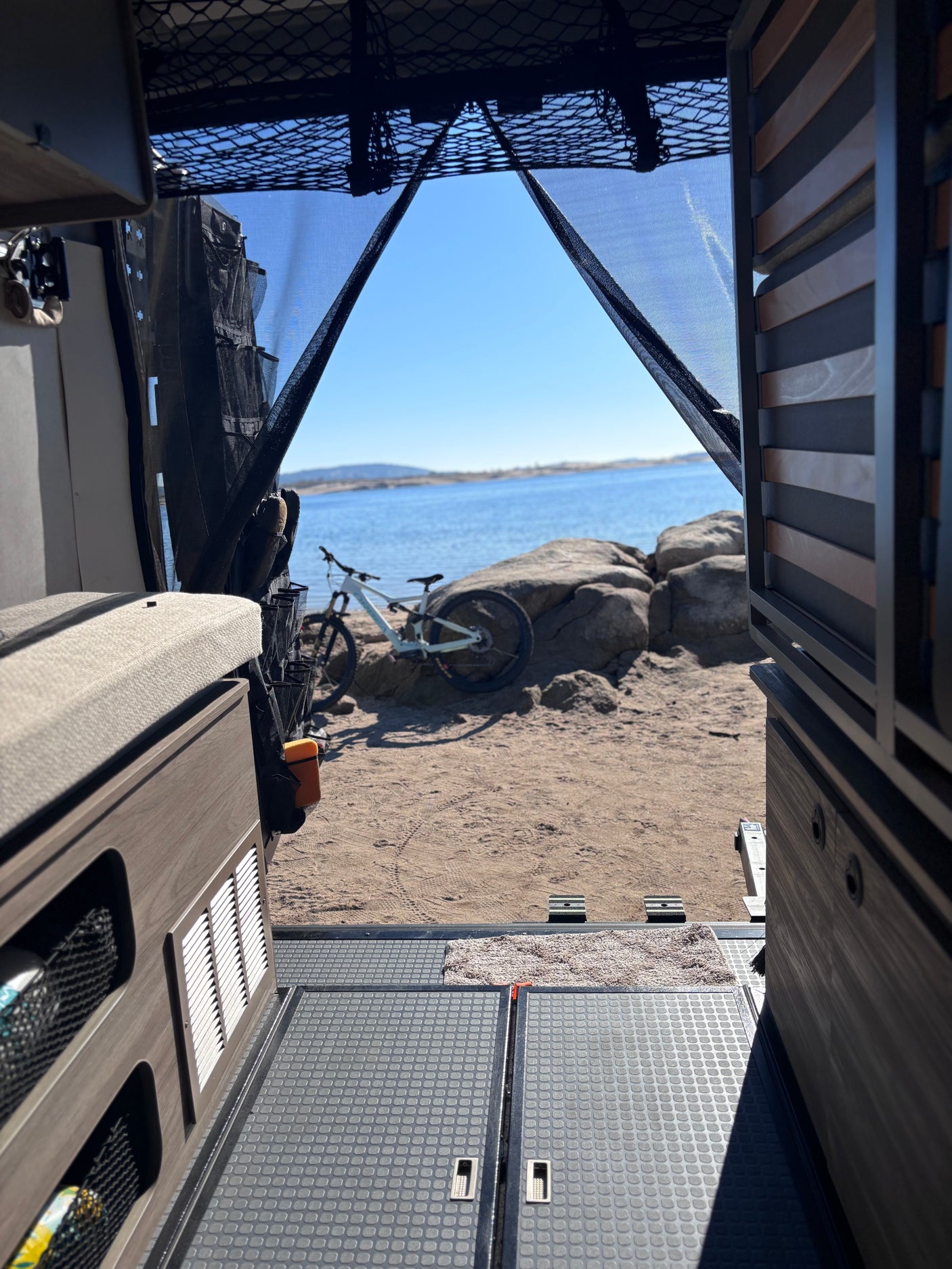 Experience adventure with an RV rental: view from inside looking out at a mountain bike by a lake.