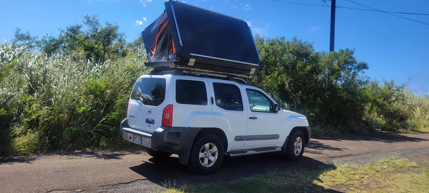 White Nissan Xterra SUV with open rooftop tent, ideal RV rental for overlanding adventures.