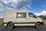 This light grey Mercedes Sprinter camper van, an ideal RV rental, is equipped with off-road tires and rooftop solar.