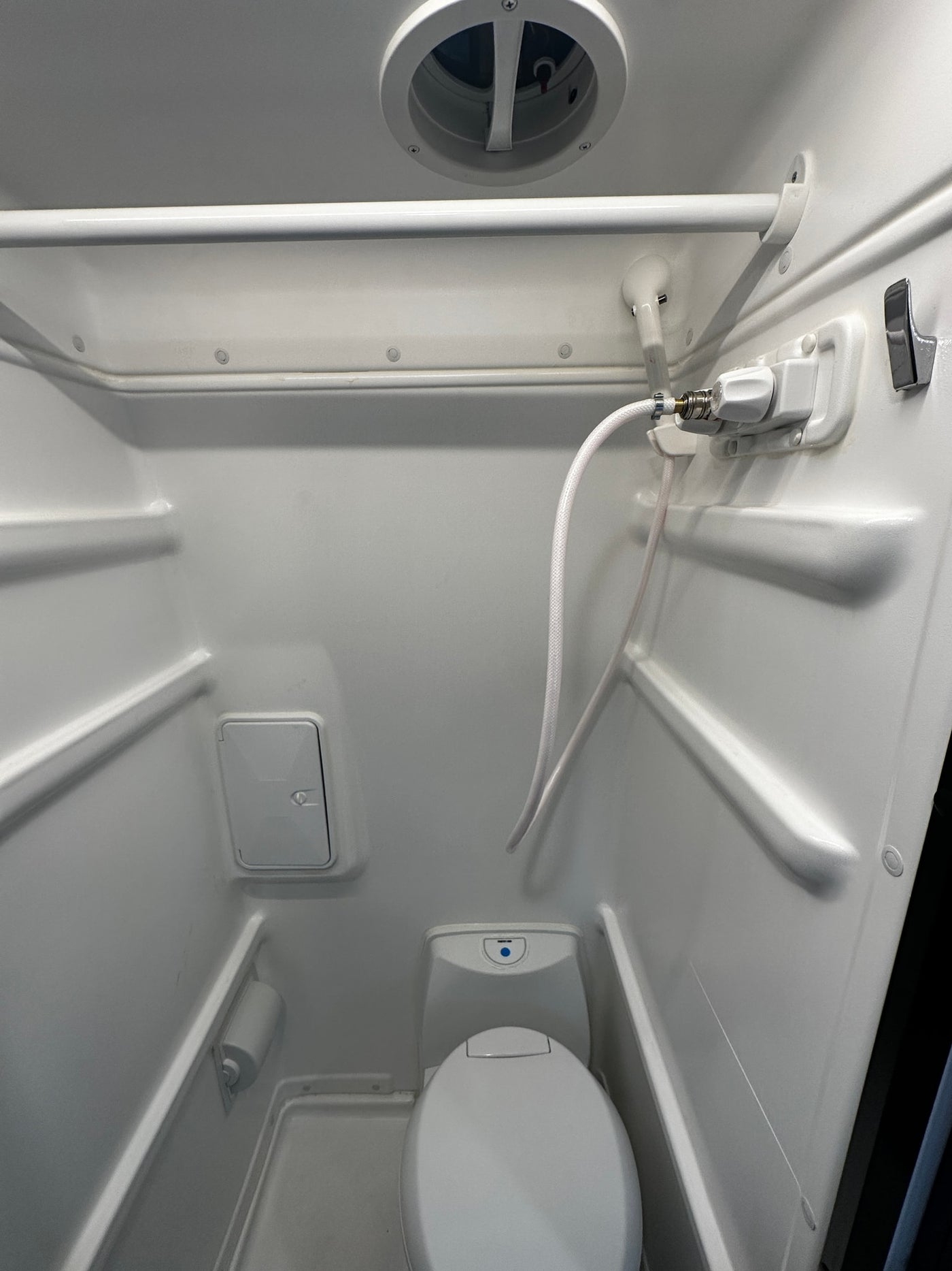 This RV rental wet bath features a toilet, handheld shower, overhead vent, and storage, all in a compact space. — photo 16