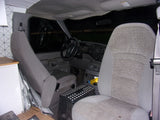 Interior of an rv rental camper van, showing the driver & passenger seats, dashboard, and a conversion cabinet on the left.